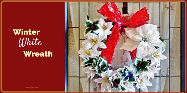 This Winter White Wreath features glitter covered silk poinsettias and contrasting green and red holly sprigs to greet family and friends this Christmas.