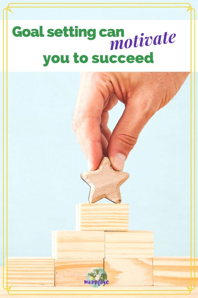 hand placing wooden star on top of wooden block pyramid and text overlay "goal setting can motivate you to succeed"