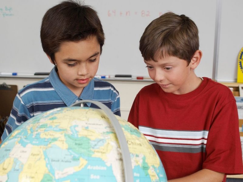 two boys studying a globe