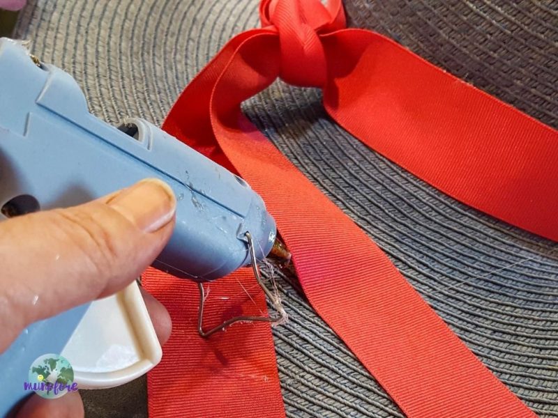 glue gun gluing pink ribbon to hat