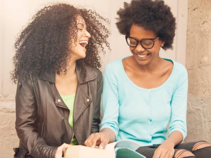 two friends talking and looking at a book