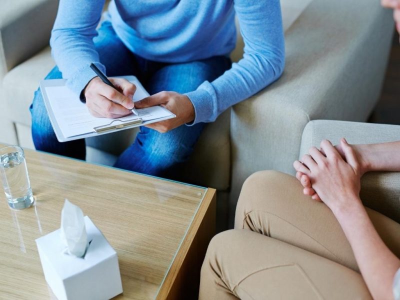 two people sitting at a table with one taking notes